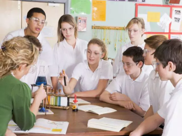 pupils around table with chemicals in test tubes