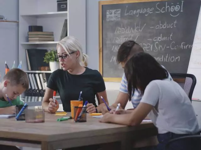 language teacher sitting at table with three pupils