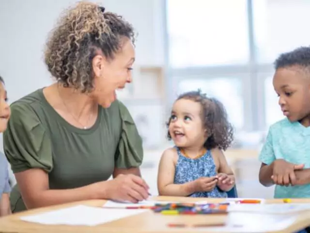 woman laughing teaching children around a table